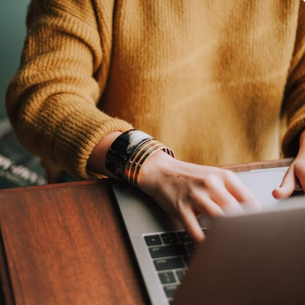 woman's hands and typing on laptop